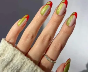 "Hand with nails painted in sparkling green and red design, wearing a silver ring."