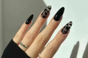 Hand showcasing valentine nails with black and leopard print designs.